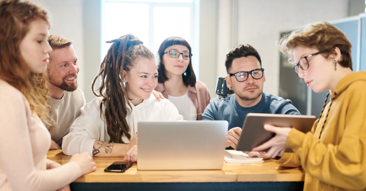 A diverse group of professionals engaged in a brainstorming session around a wooden table with technology present.